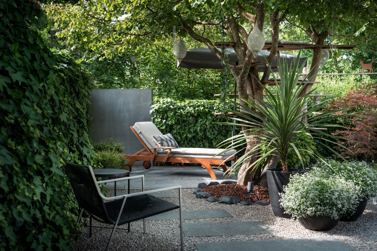 Outdoor lounge area with lounge chair, plants, small table, and modern design elements.