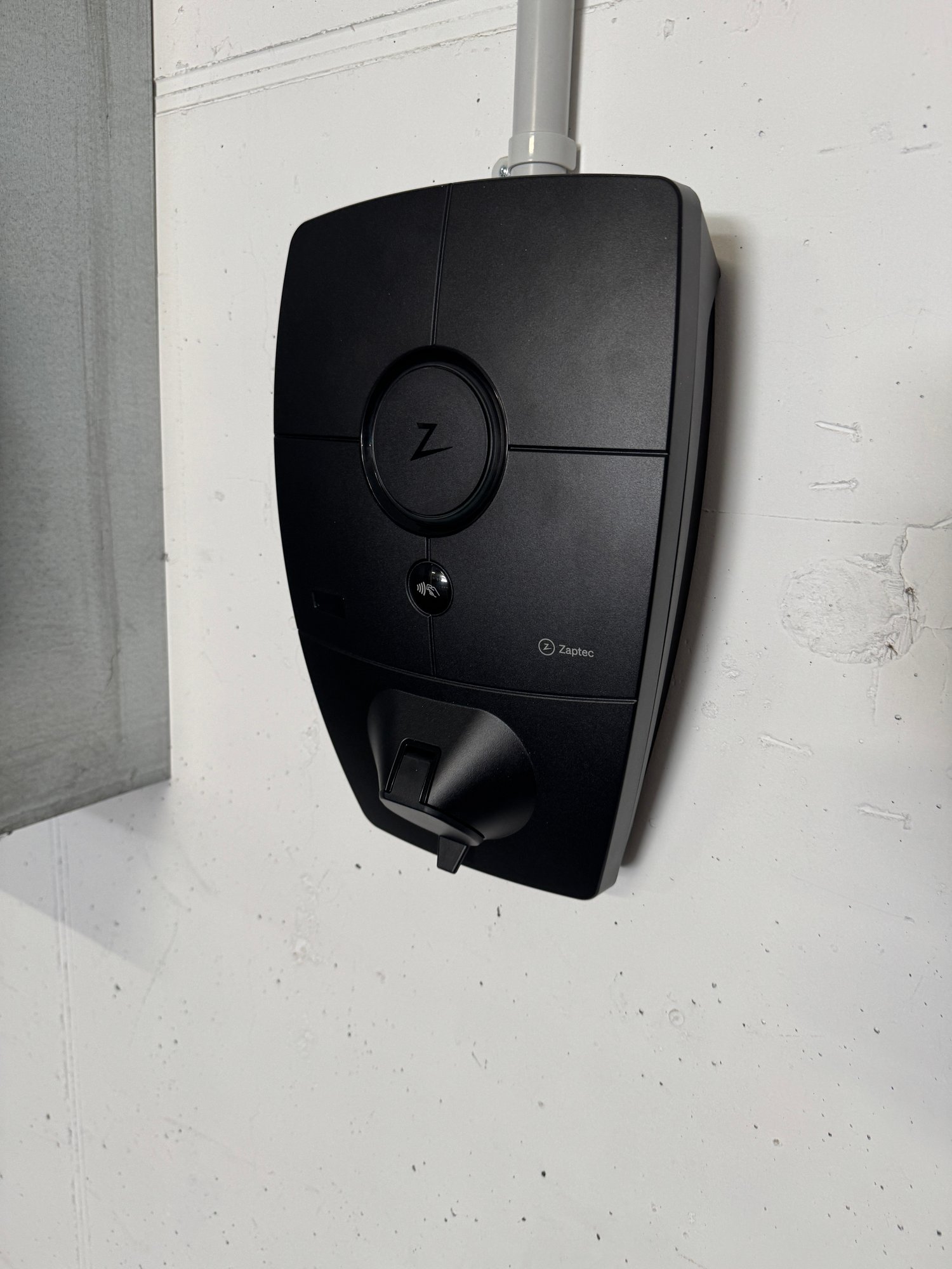 Black electric vehicle charger mounted on white wall, branded Zaptec