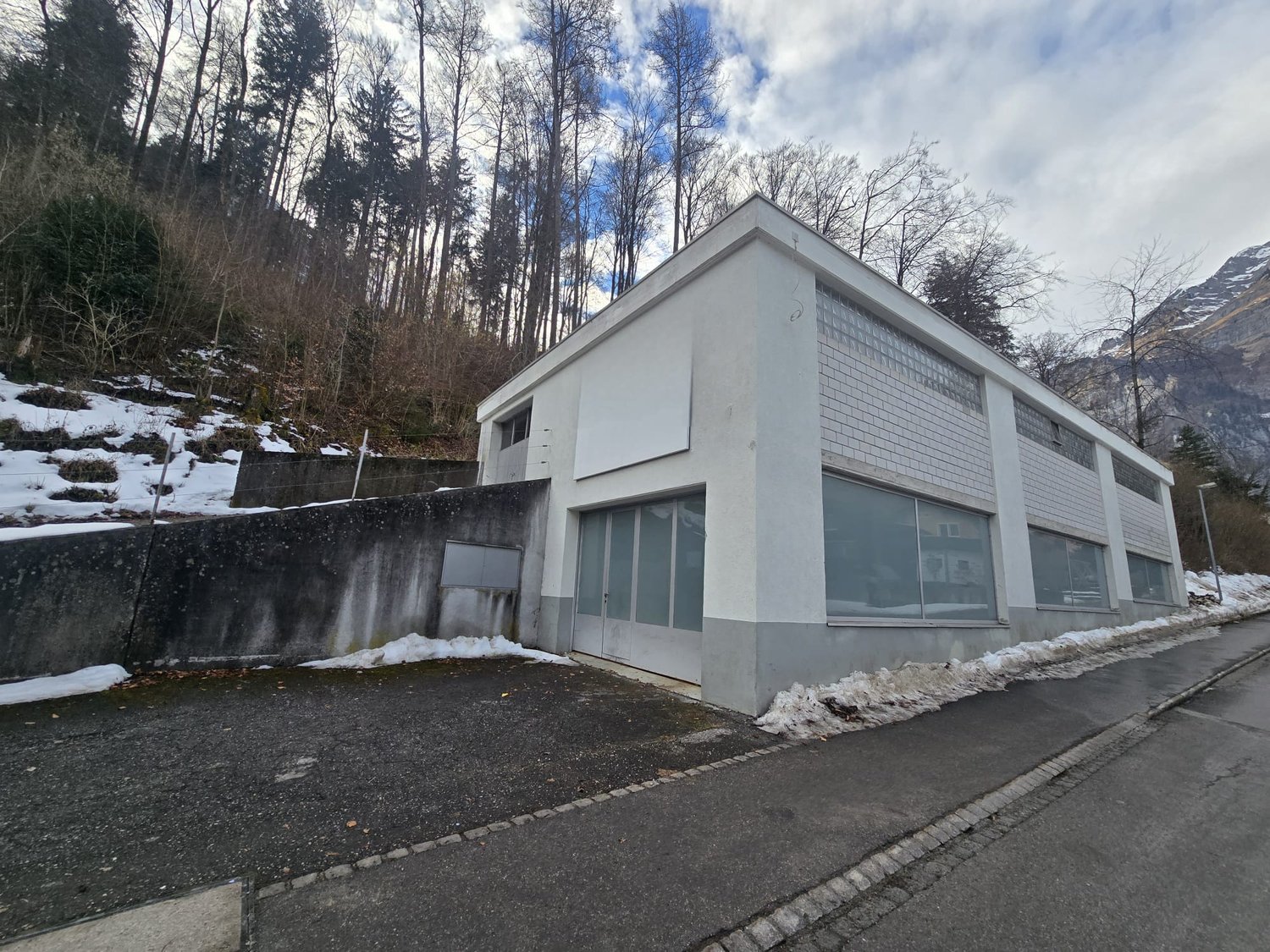 Modern building, white exterior, grey brick walls, glass windows, garage entrance, concrete walkway