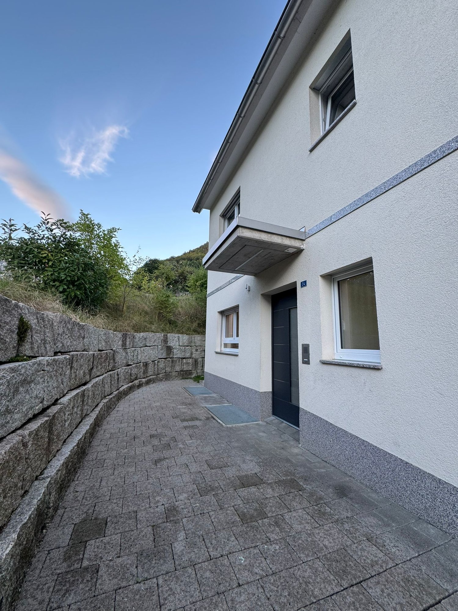 Facade of a house with entrance, windows, and a small balcony.