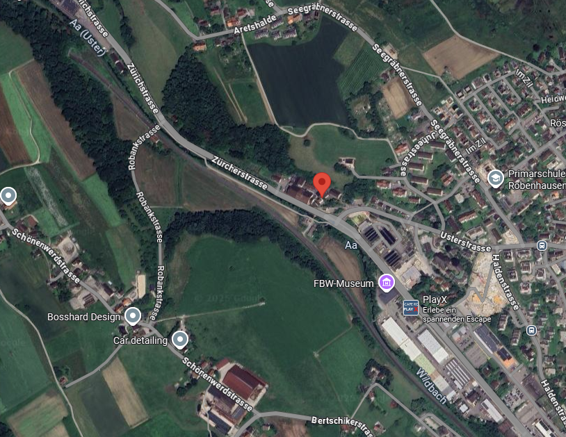 Area shows a road with green areas, buildings, a small lake, a red marker and street labels