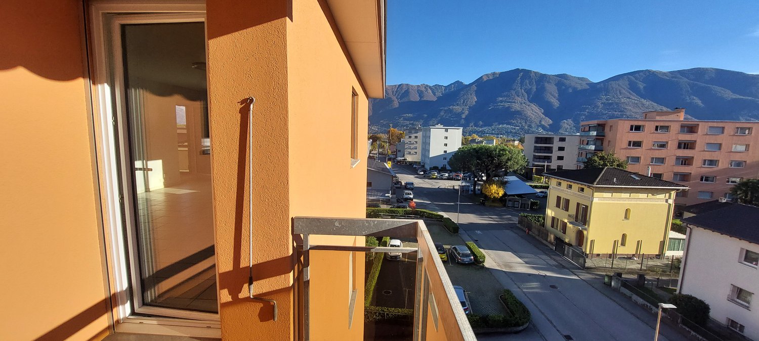 Balcony with railing, view of the mountains, road with cars, buildings