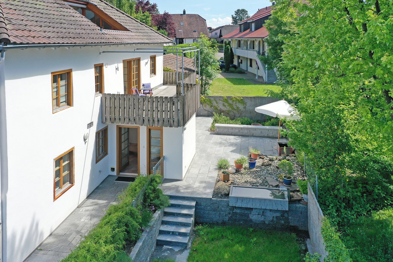 white house, brown roof, balcony, paved patio, garden, steps