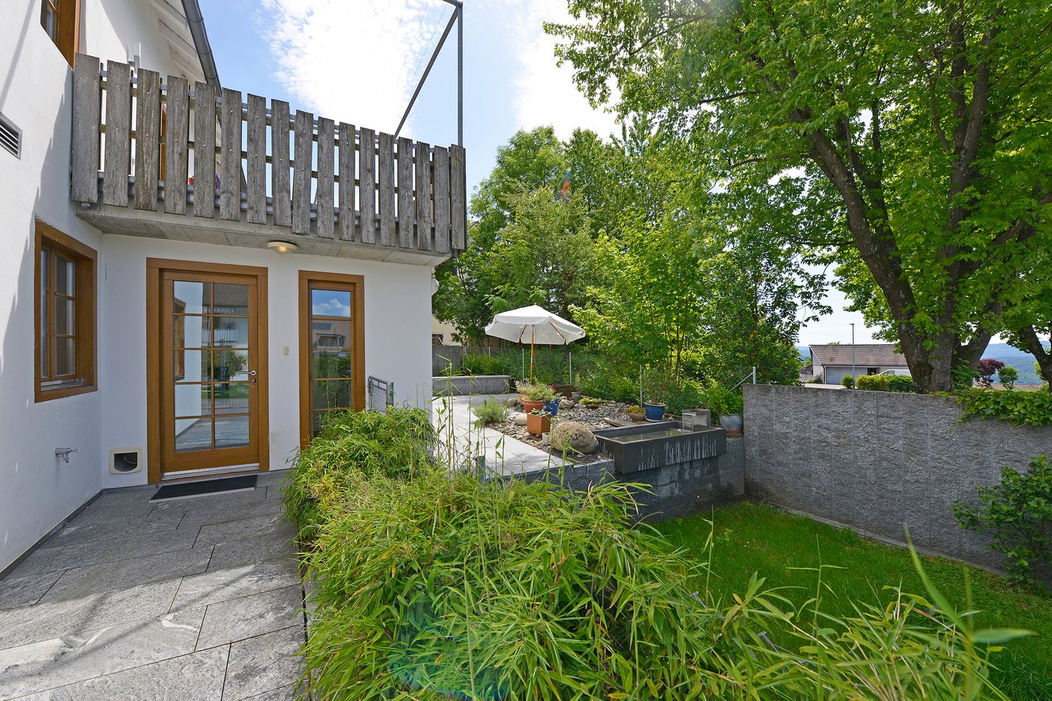 balcony, stone patio, wooden door, outdoor plants, stone wall, umbrella