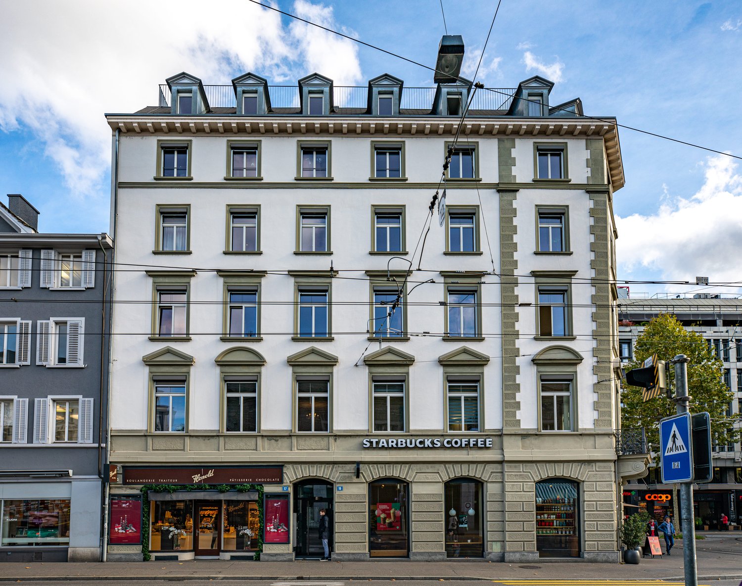 white facade, multiple windows, Starbucks Coffee shop on the ground floor, streetlights and wires above