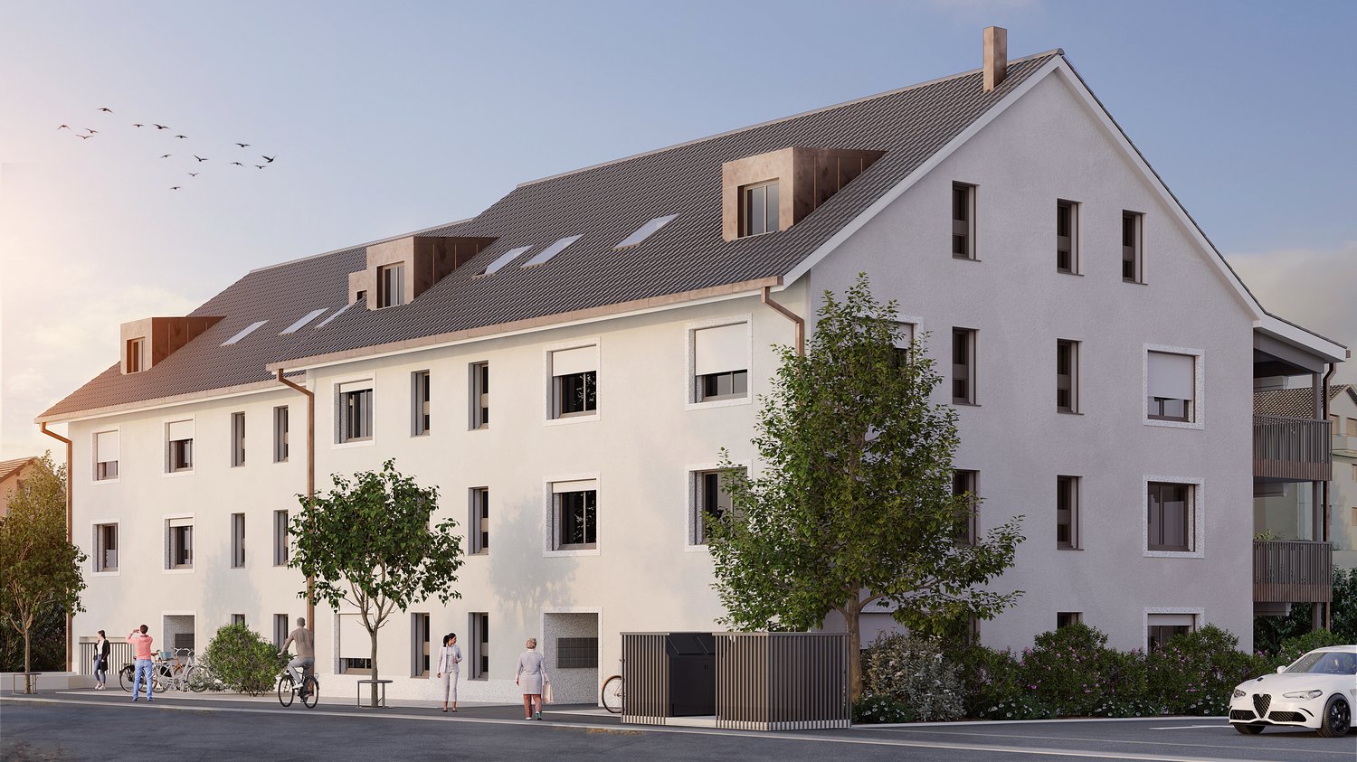 A multi-story apartment building with a gray exterior, a slanted roof, and several windows. There are trees and landscaping around the building, and a car parked in front. The building appears to have a modern, residential design.