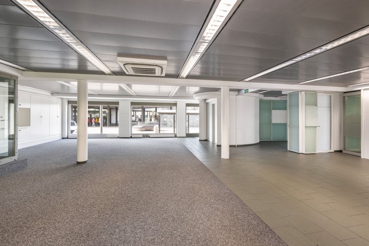 wide open space, carpet flooring, tiled flooring, metal beams, glass walls, white walls, columns