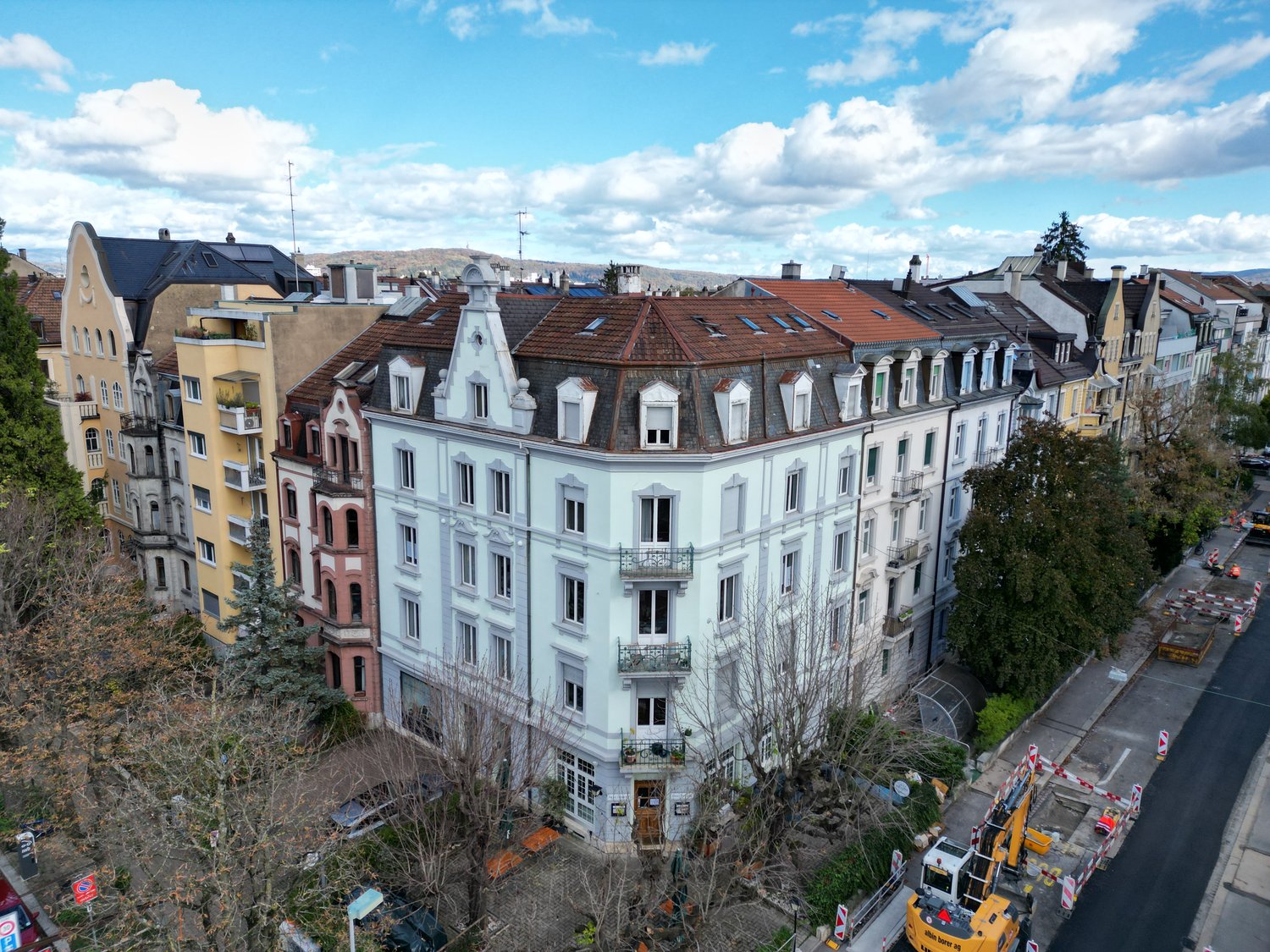 Multi-story building with multiple balconies and a mix of architectural styles, located in a city setting
