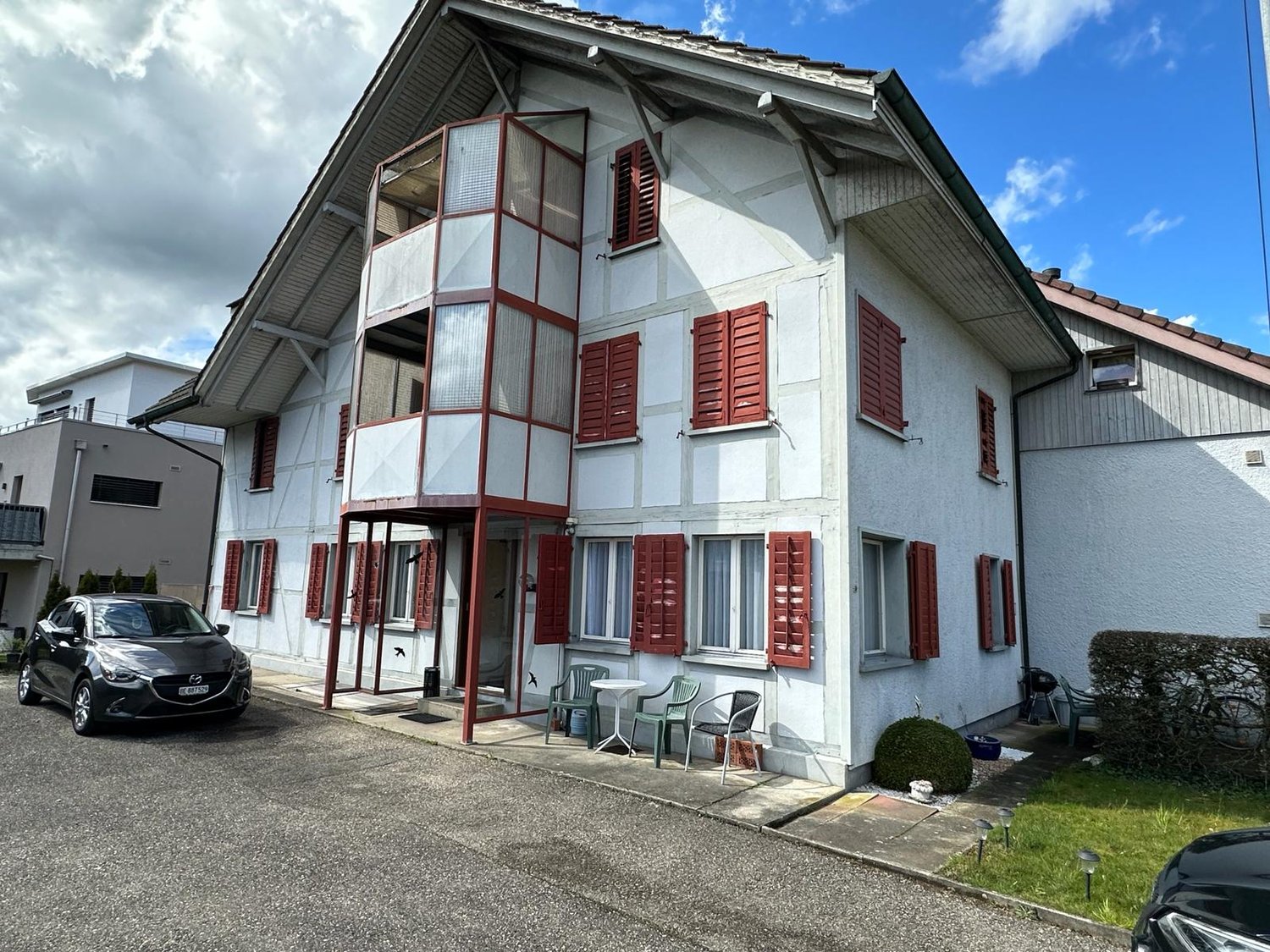 2 story house, white exterior, red shutters, balcony, car parked in front