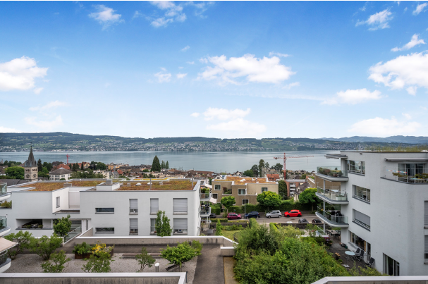 Modern white building, green roof, balcony, view of the lake and mountains