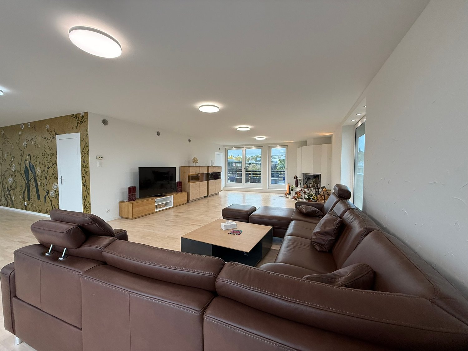 U-shaped sofa, TV, wooden coffee table, wood floor, sliding windows, wooden storage