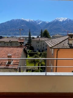 Outdoor balcony with a view of the mountains and buildings.
