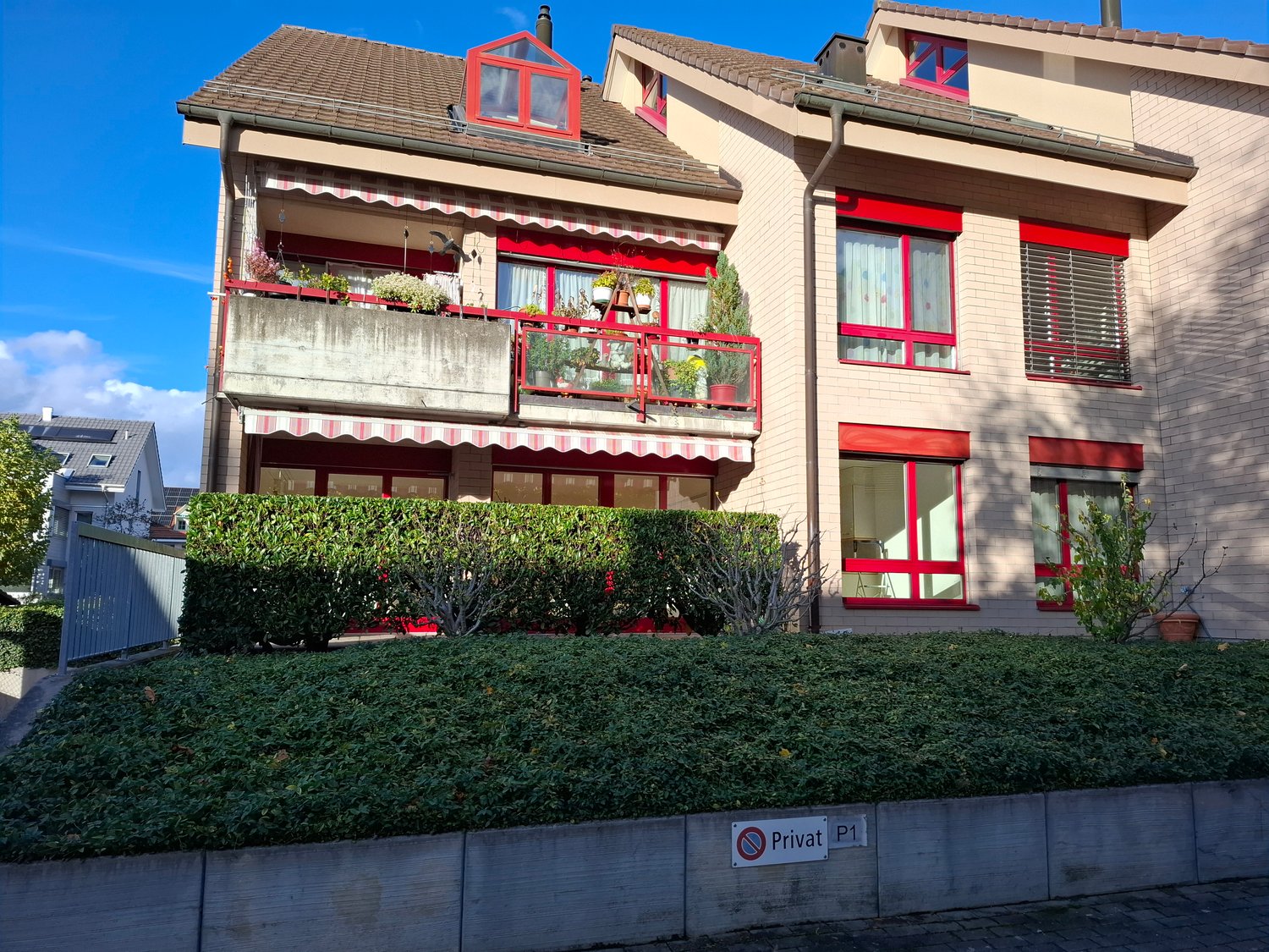 2 story beige house, red trims, balcony on second floor