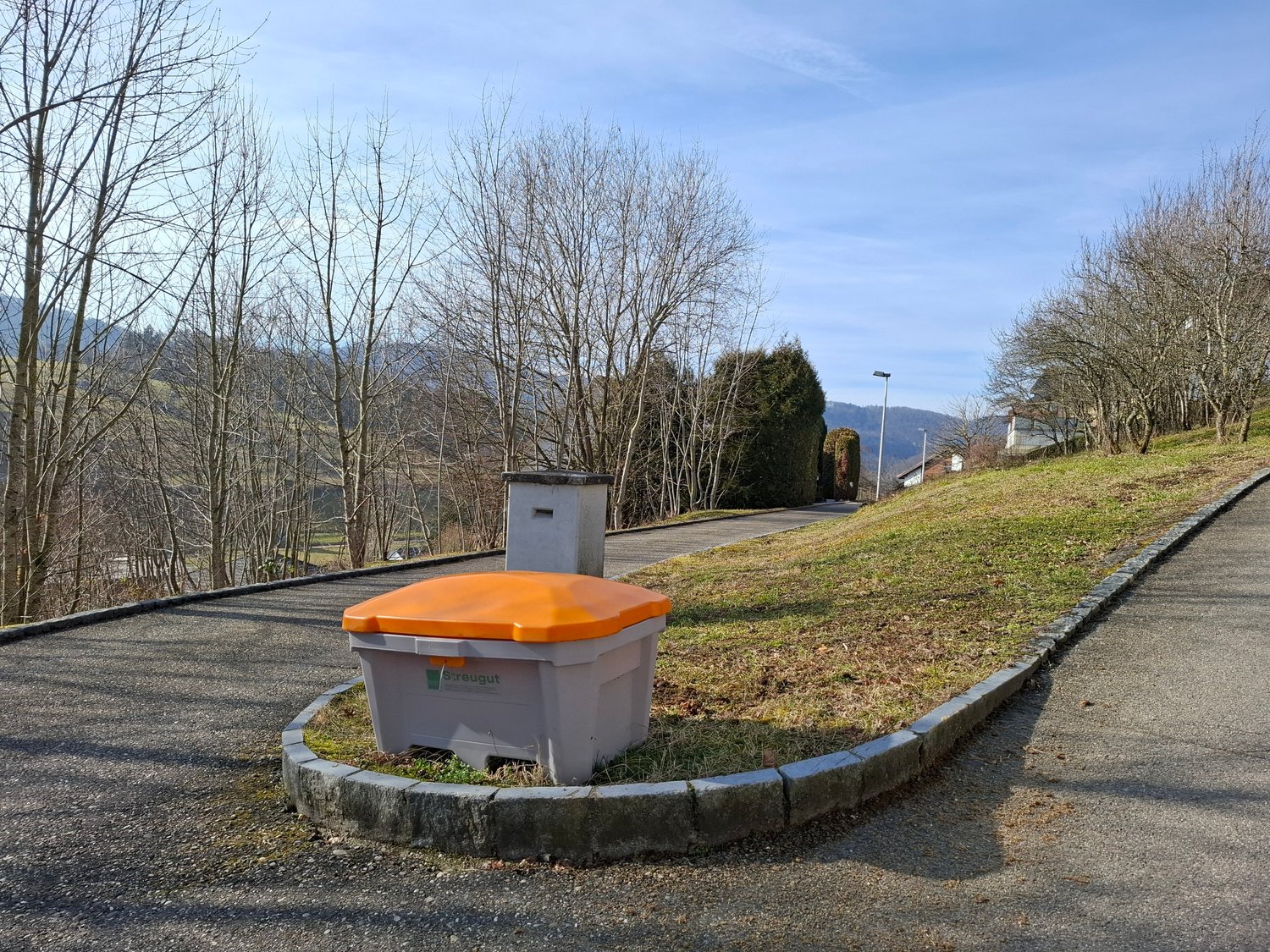 residential area, roadside waste container, slope, greenery, clear sky