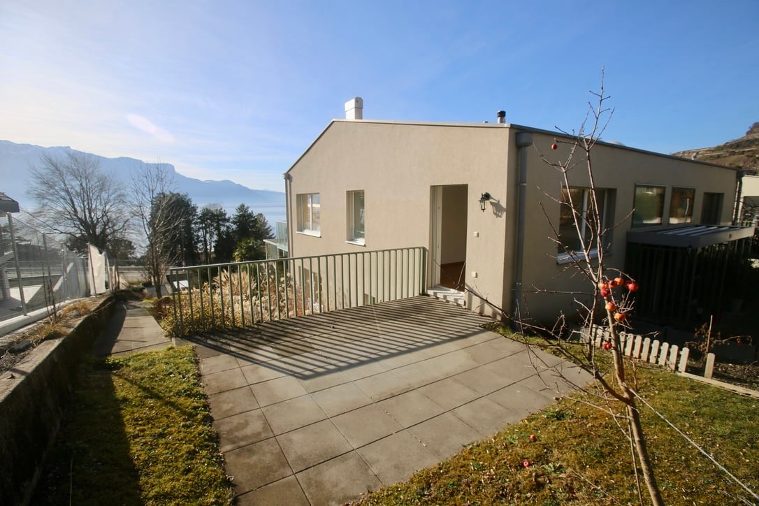 Raised single story house, concrete floor, glass entrance, large windows, pathway